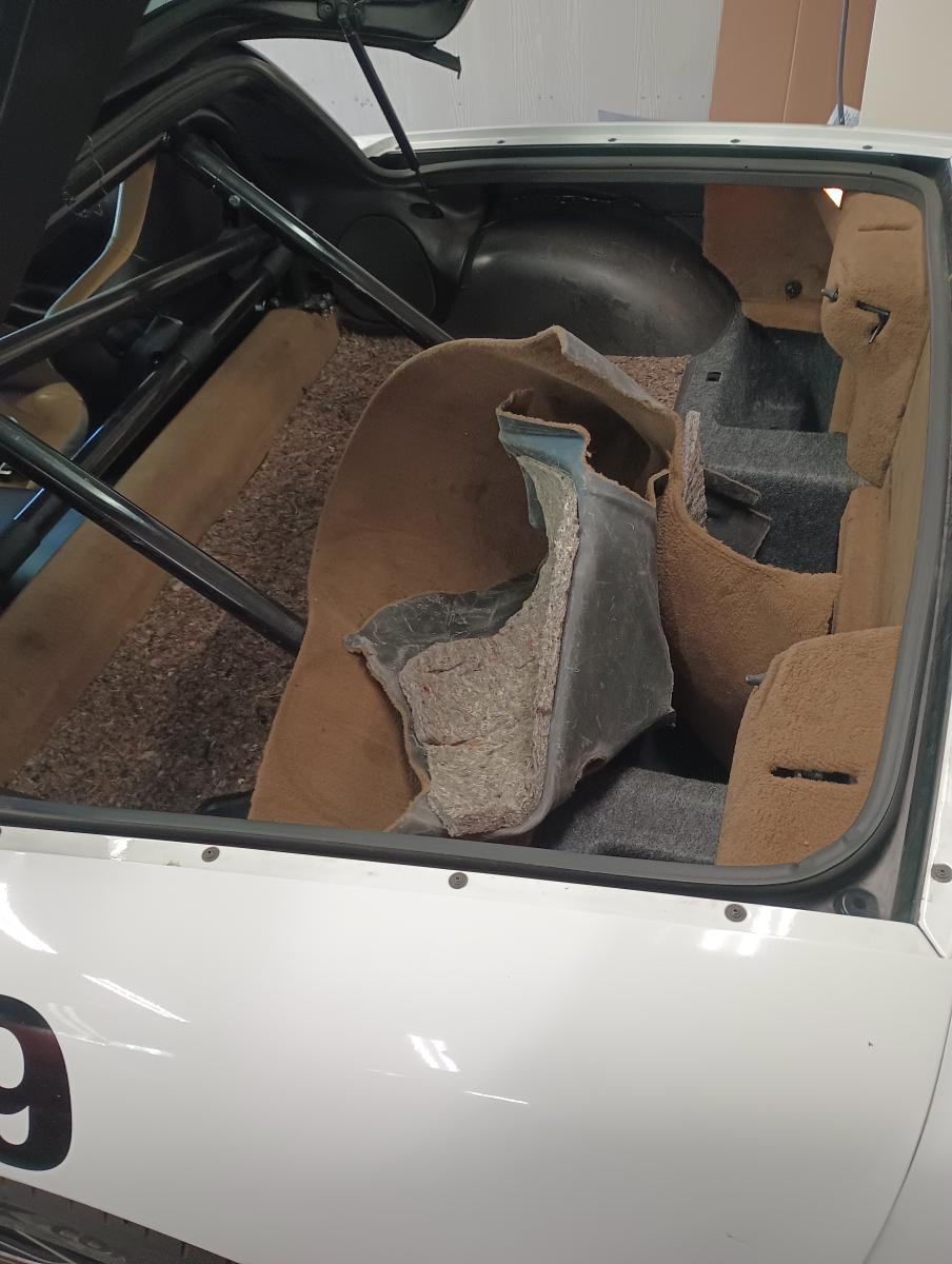 C5 Corvette Targa top rear compartment with the carpet and padding underneath partially pulled out to demonstrate the process Jesse is understaking of removing weight from the rear of the car.
